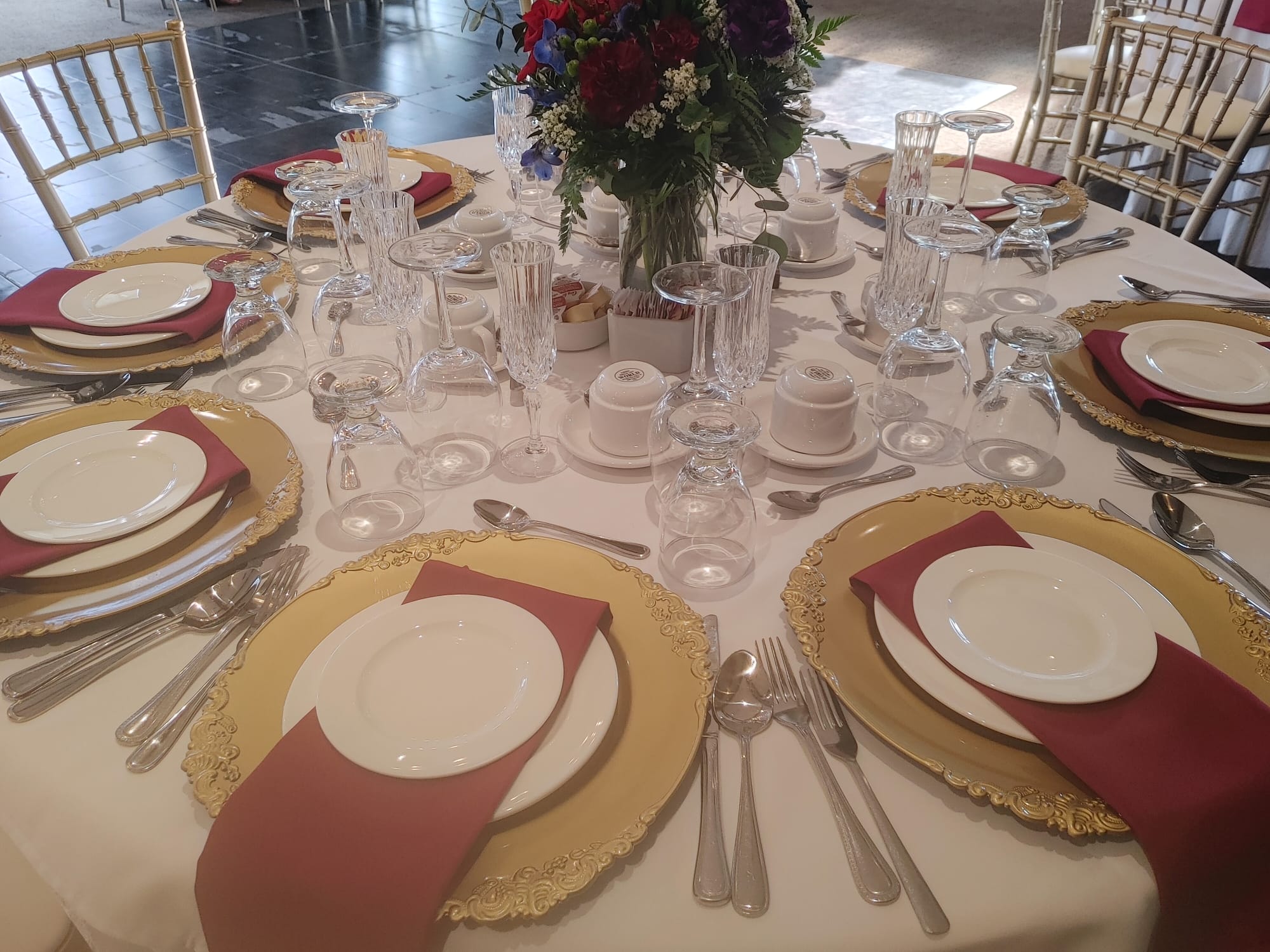 Wedding reception table setting with gold chargers and floral centerpiece at Foxbridge Golf Club